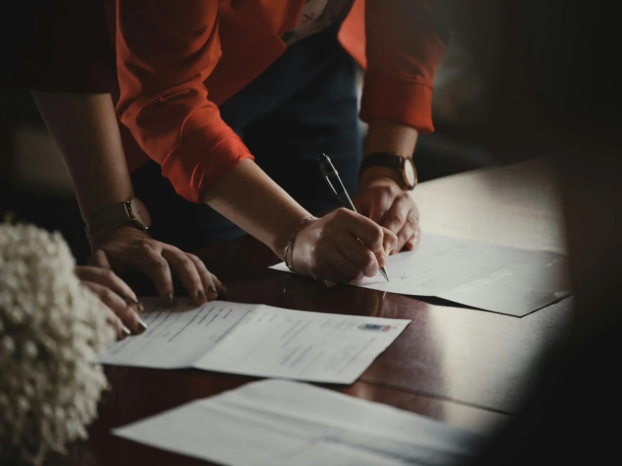 Adviser writing notes on documents during a client meeting
