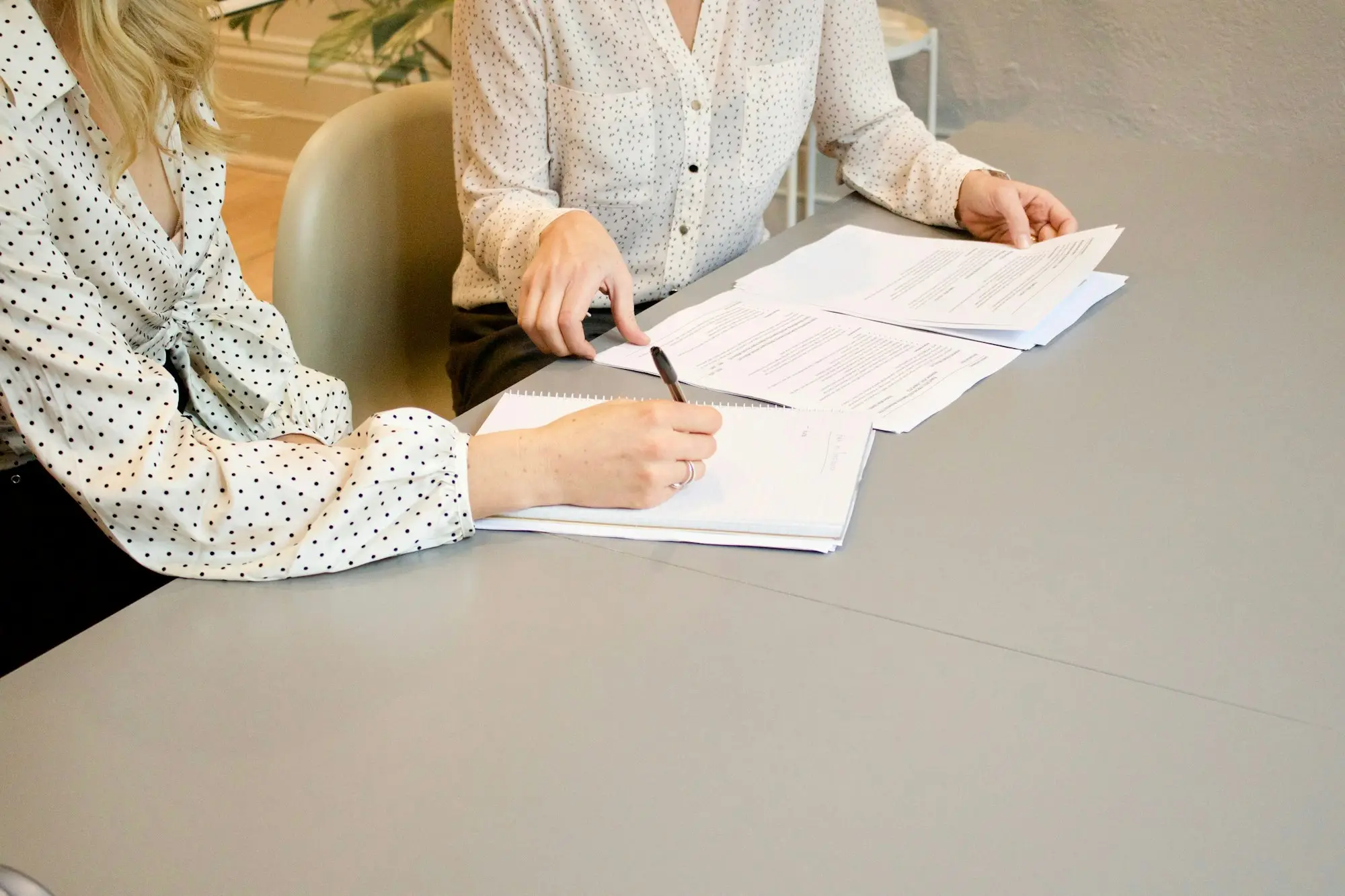Business owner signing loan documents while an adviser points to the page